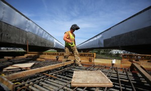 Huberto Deleon of C.C. Myers walks on rebar between the northbound and southbound sides of the current Petaluma River bridge, which have been covered with plastic sheeting to keep cliff swallows from nesting. (Crista Jeremiason / The Press Democrat)